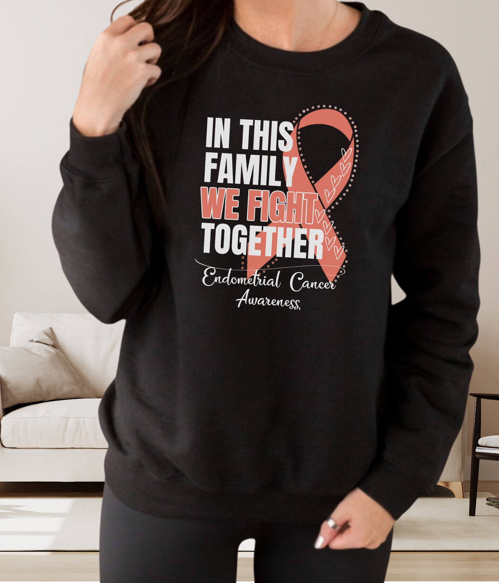 a woman wearing a black sweatshirt with a pink ribbon on it