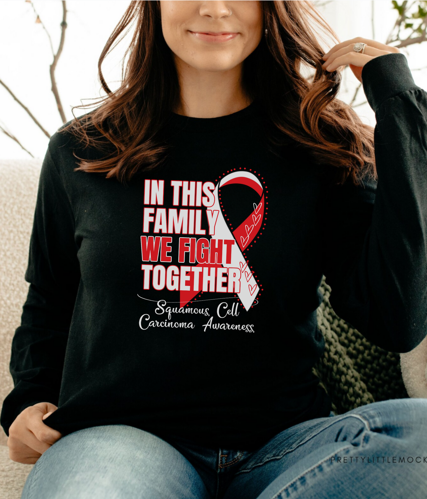a woman sitting on a couch wearing a black shirt with a red ribbon on it