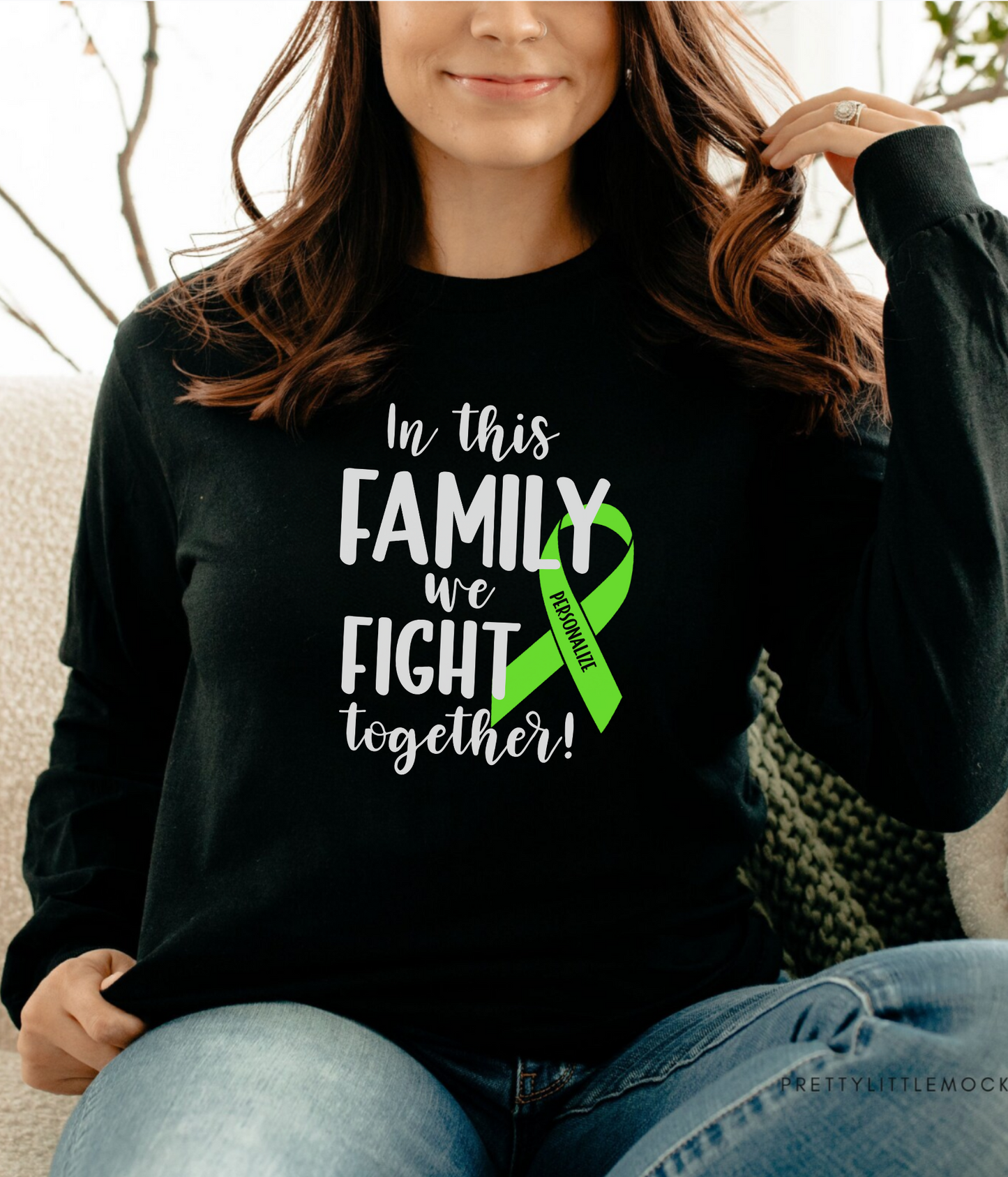 a woman sitting on a couch wearing a black shirt with a green ribbon