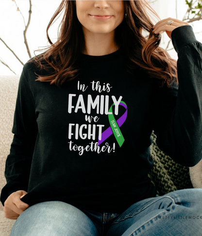 a woman sitting on a couch wearing a black shirt with a purple and green ribbon