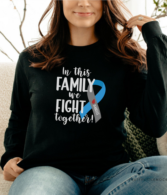 a woman sitting on a couch wearing a black shirt with a blue ribbon on it