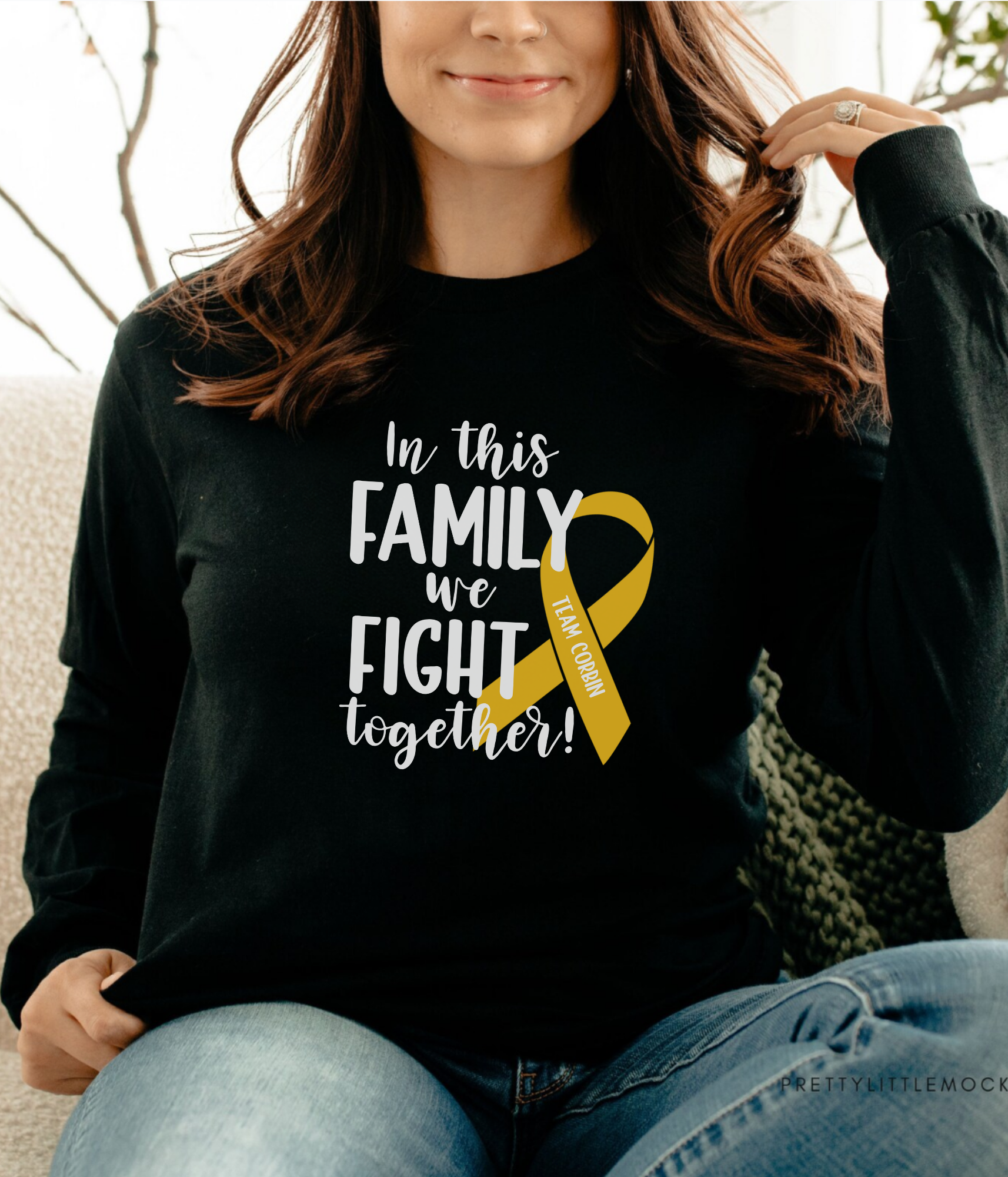 a woman sitting on a couch wearing a black shirt with a yellow ribbon