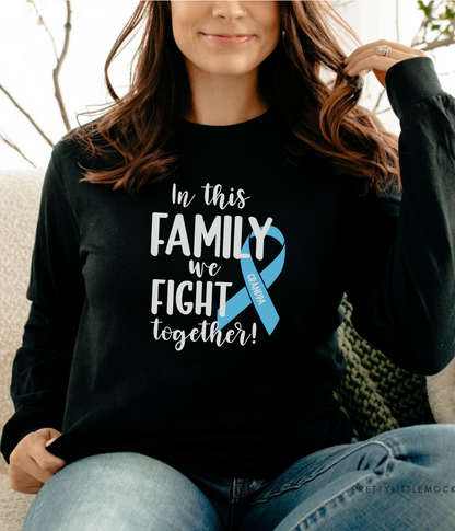 a woman sitting on a couch wearing a black shirt with a blue ribbon on it