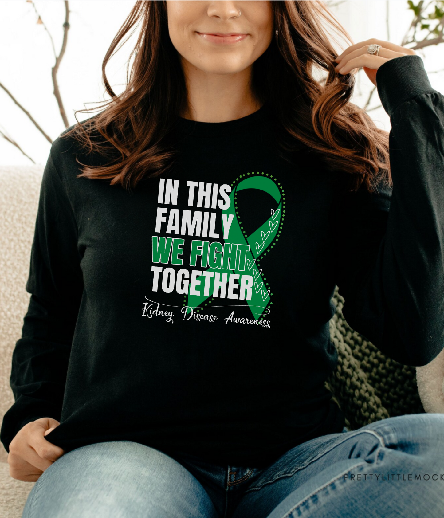 a woman sitting on a couch wearing a black shirt with a green ribbon