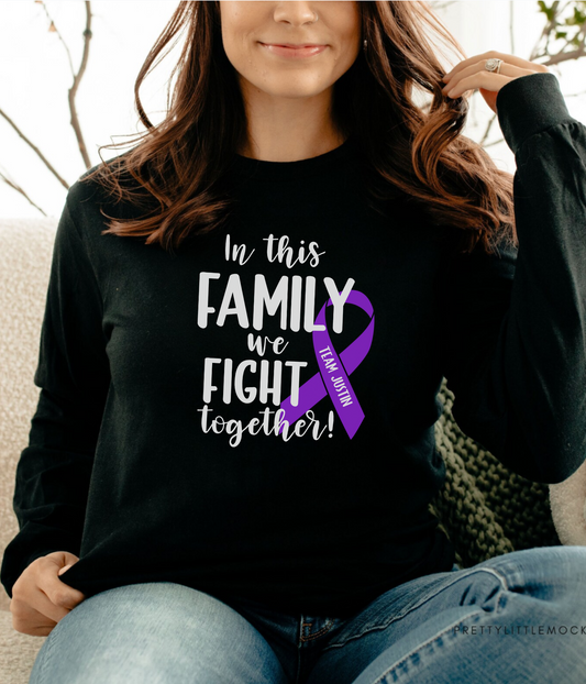 a woman sitting on a couch wearing a black shirt with a purple ribbon