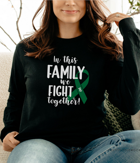 a woman sitting on a couch wearing a black shirt with a green ribbon