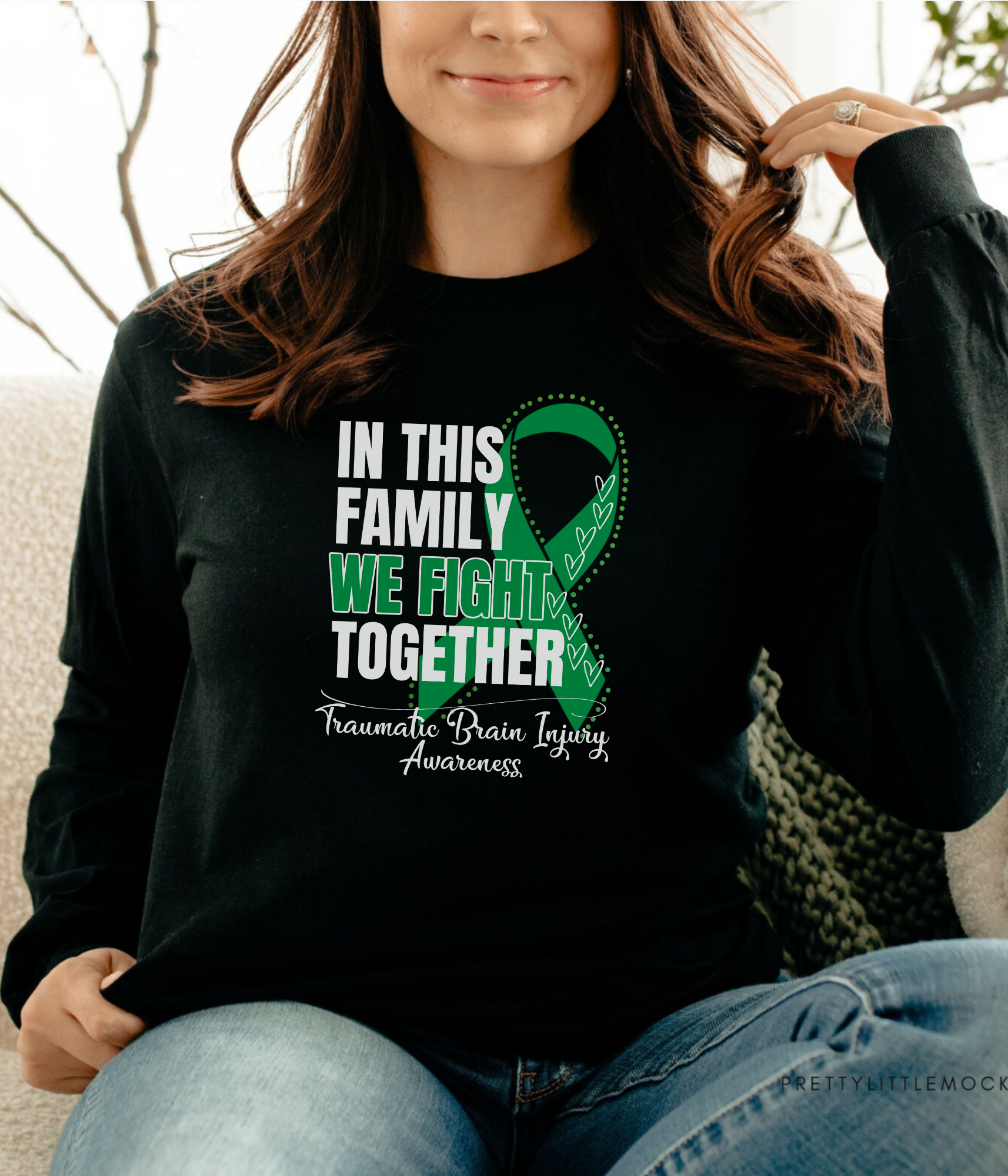 a woman sitting on a couch wearing a black shirt with a green ribbon