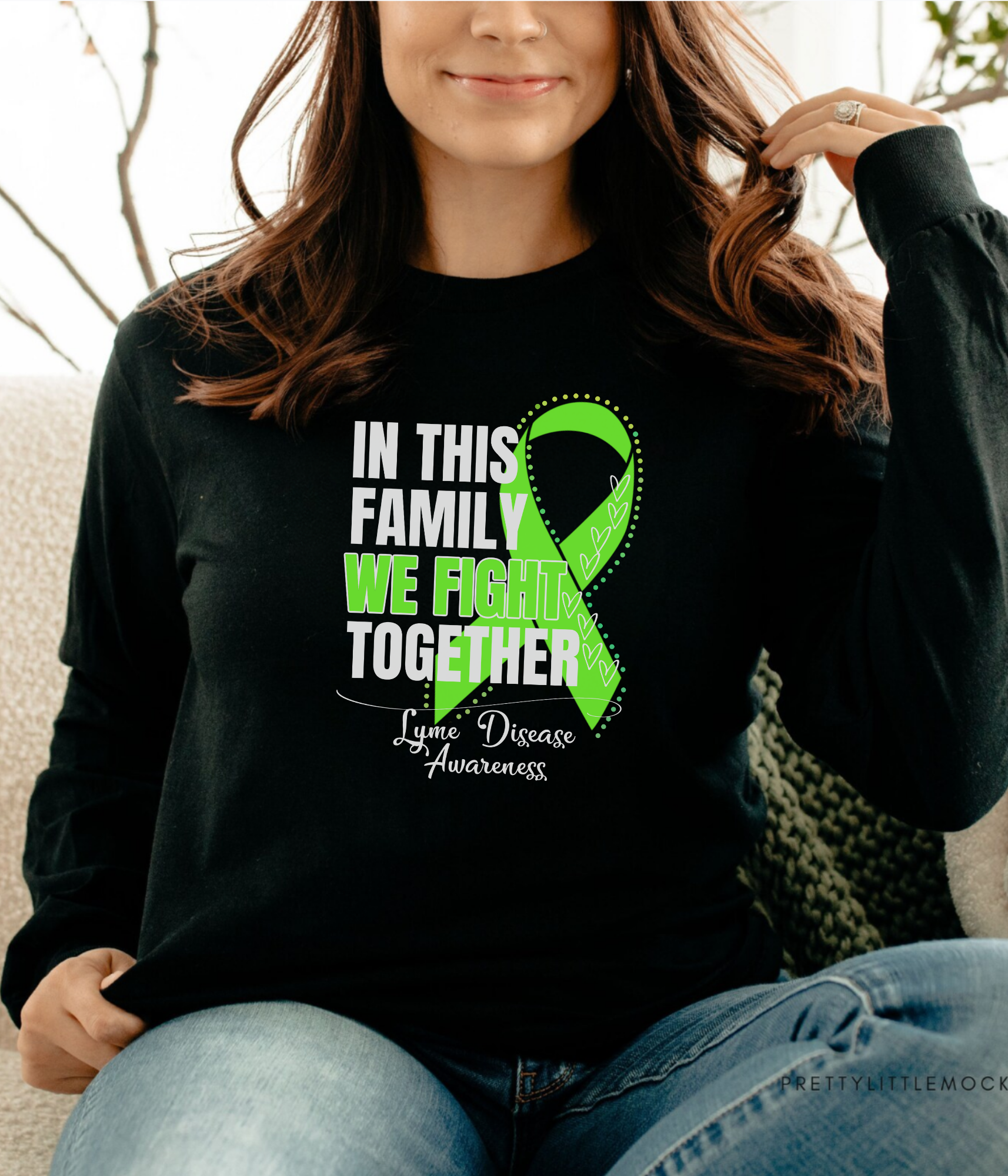 a woman sitting on a couch wearing a black shirt with a green ribbon