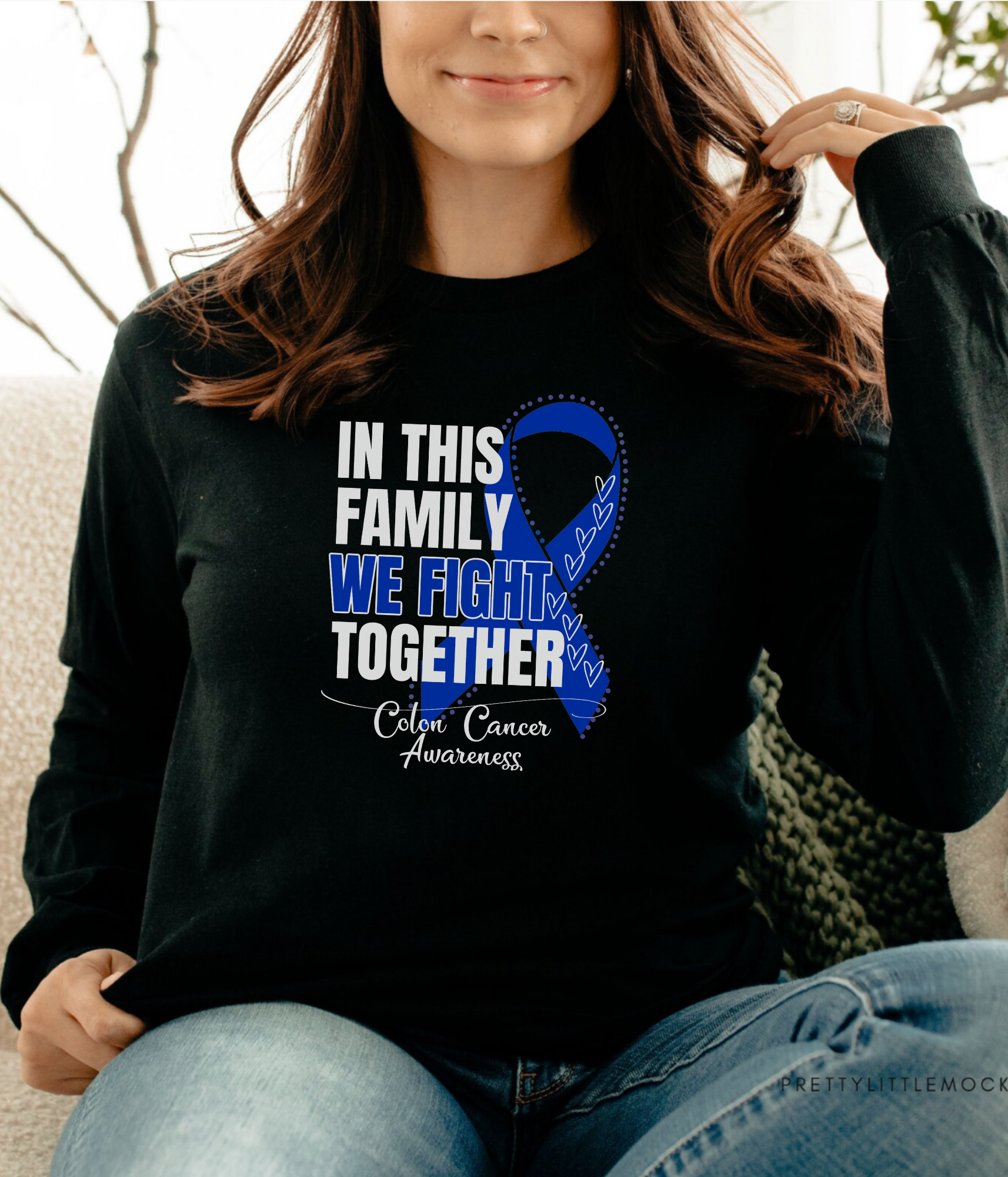 a woman sitting on a couch wearing a black shirt with a blue ribbon