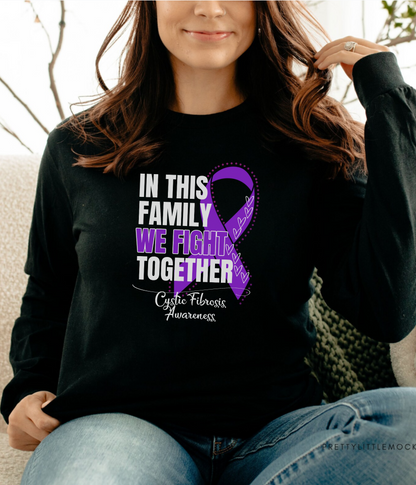 a woman sitting on a couch wearing a black shirt with a purple ribbon