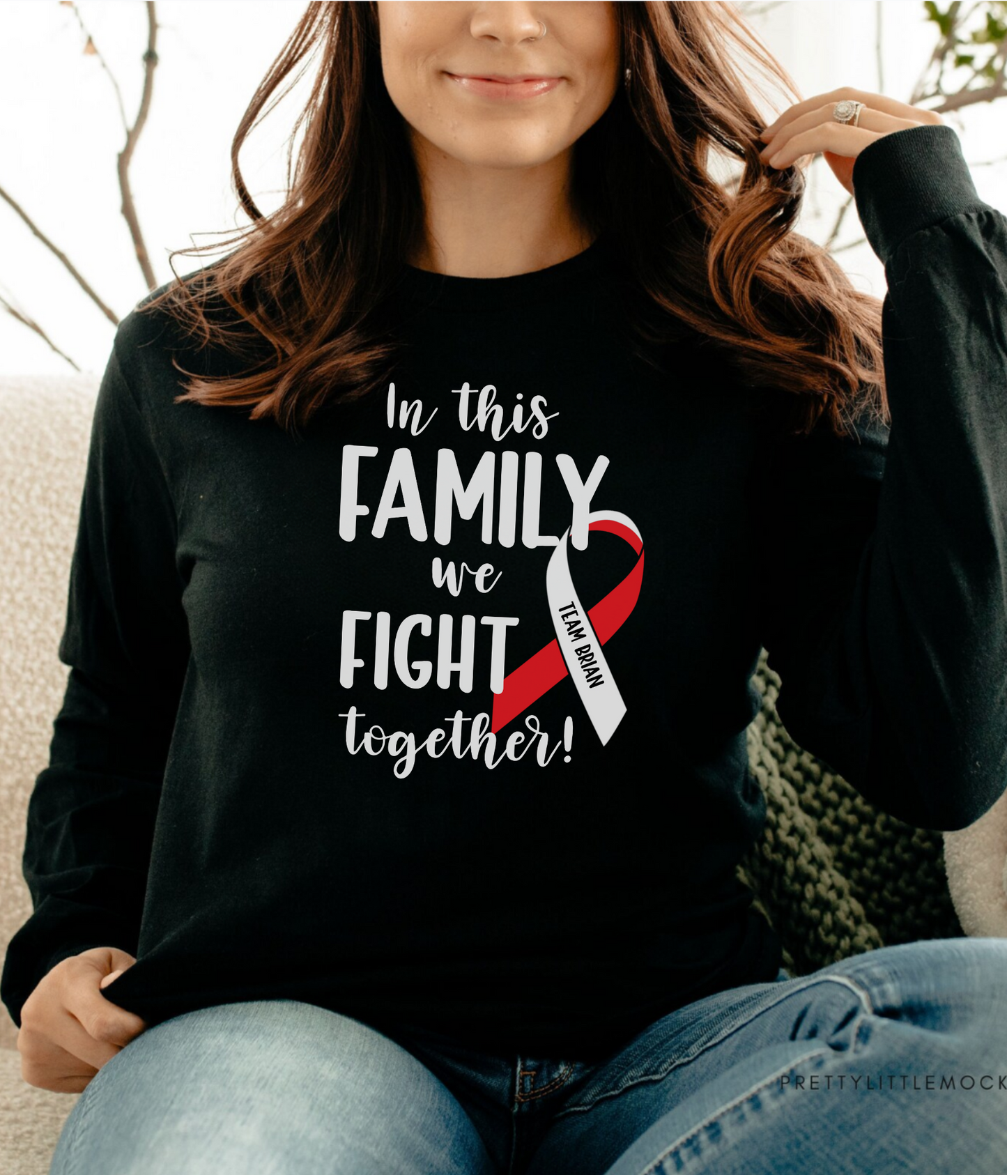 a woman sitting on a couch wearing a black shirt that says in this family we