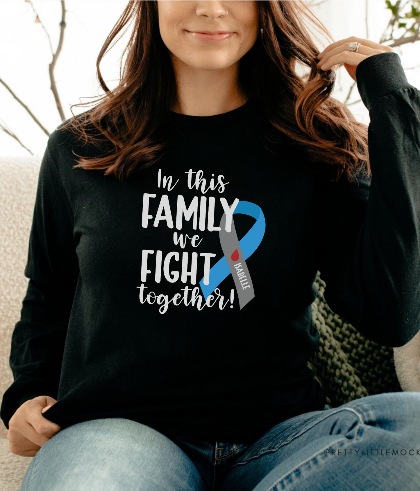 a woman sitting on a couch wearing a black shirt with a blue ribbon on it