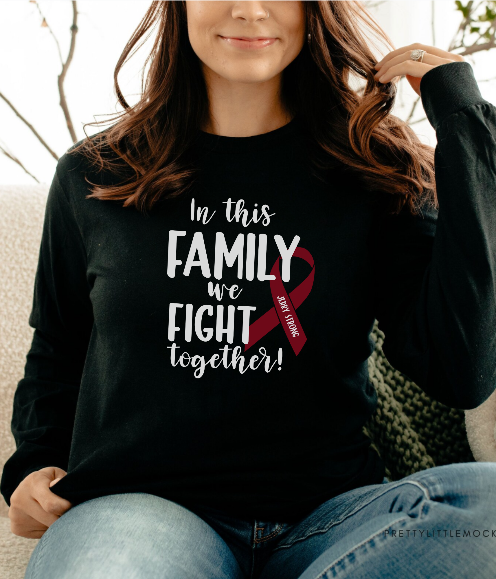 a woman sitting on a couch wearing a black shirt with a red ribbon on it