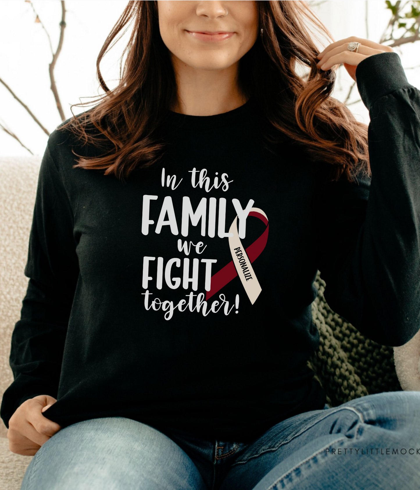 a woman sitting on a couch wearing a black shirt with a red and white ribbon