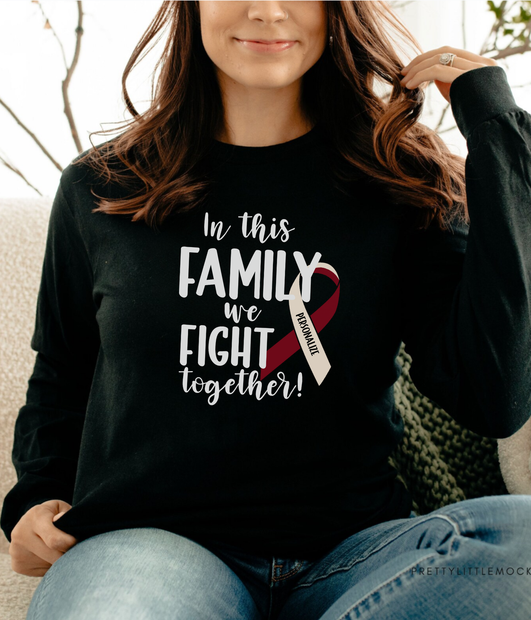 a woman sitting on a couch wearing a black shirt with a red and white ribbon