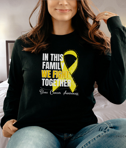 a woman sitting on a bed wearing a black shirt with a yellow ribbon on it