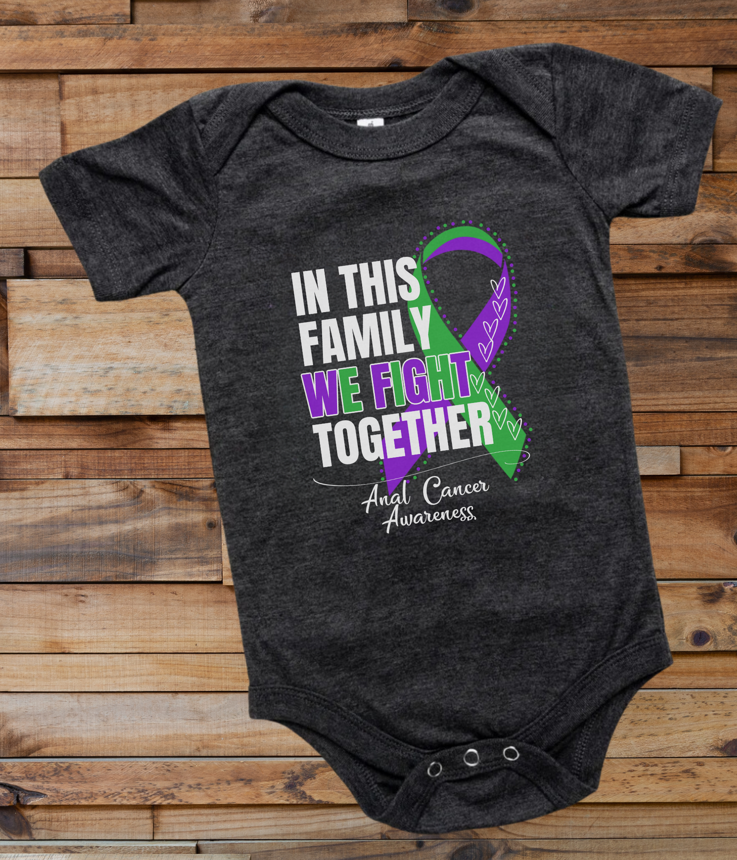 a black onesuit with a purple and green ribbon in this family we fight together