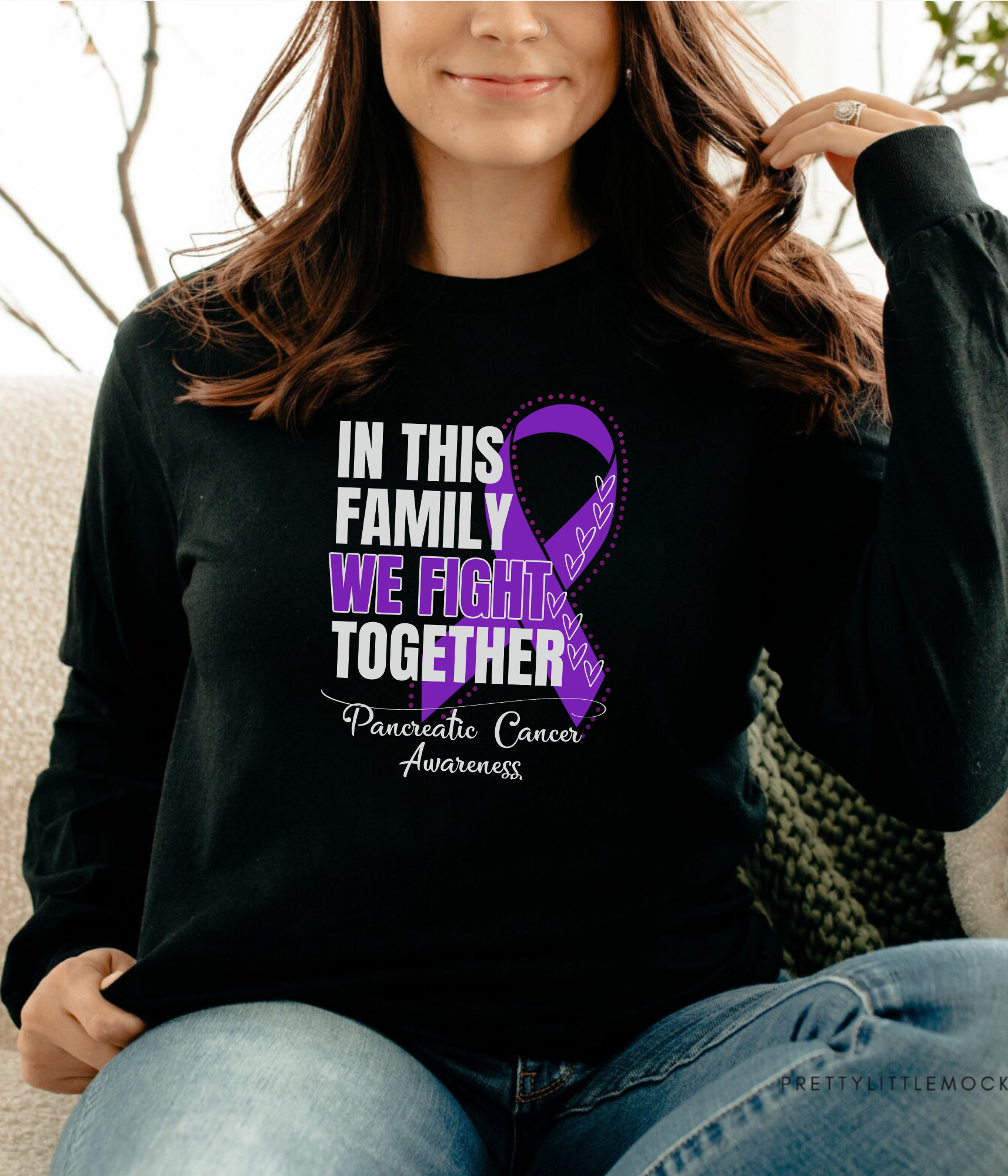 a woman sitting on a couch wearing a black shirt with a purple ribbon