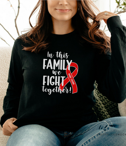 a woman sitting on a couch wearing a black shirt with a red ribbon on it