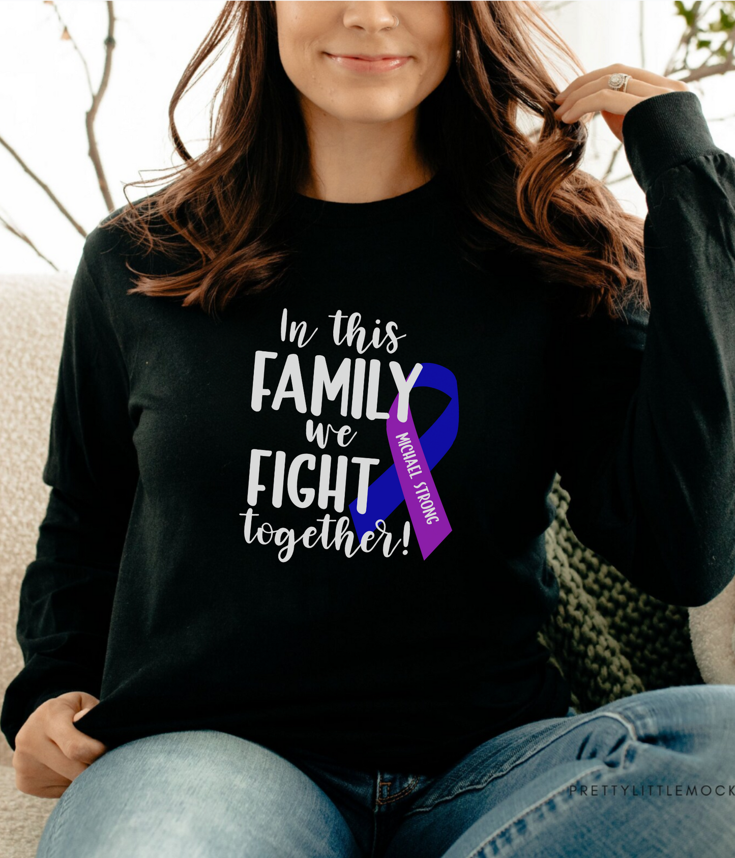 a woman sitting on a couch wearing a black shirt with a purple ribbon