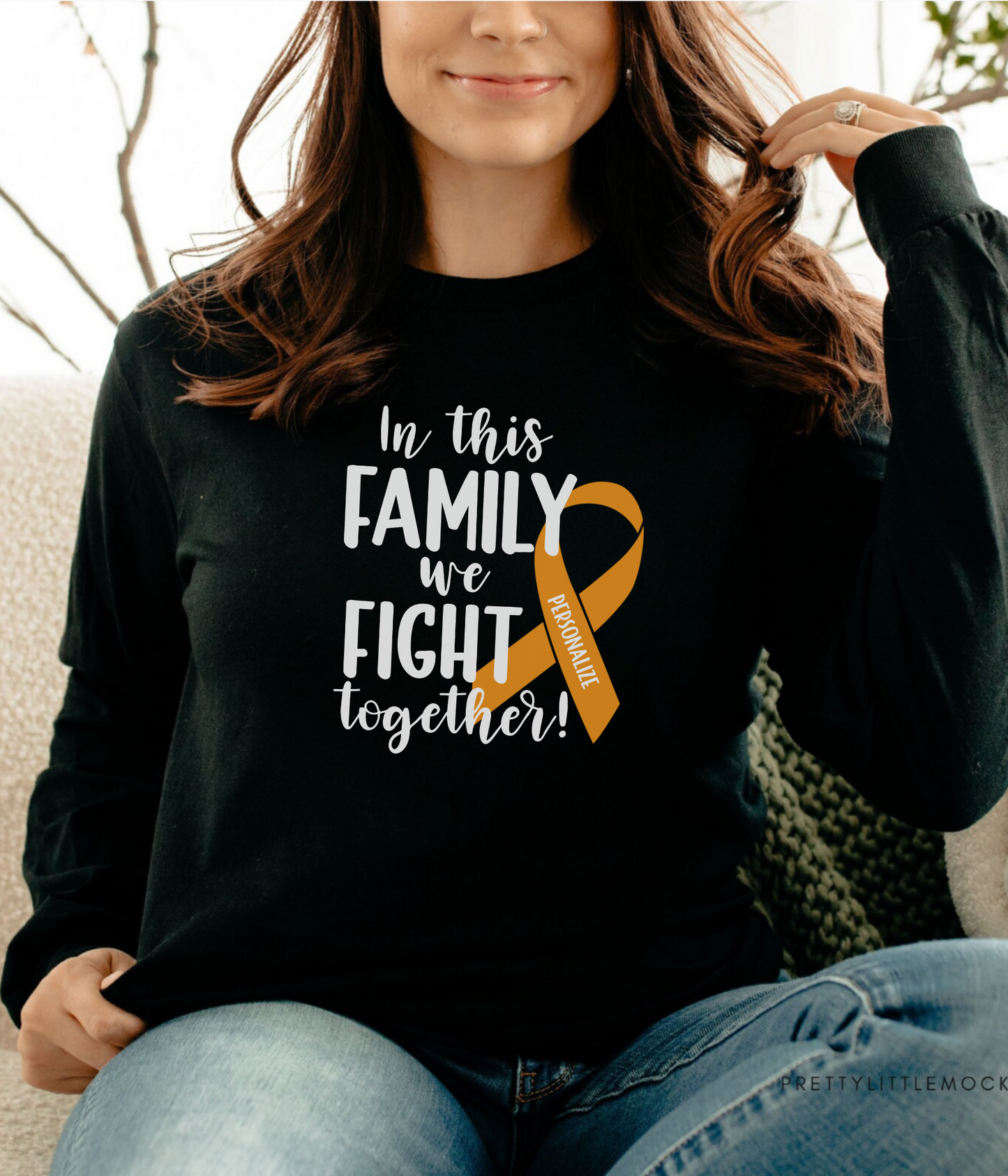 a woman sitting on a couch wearing a black shirt with an orange ribbon