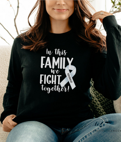 a woman sitting on a couch wearing a black shirt that says, in this family