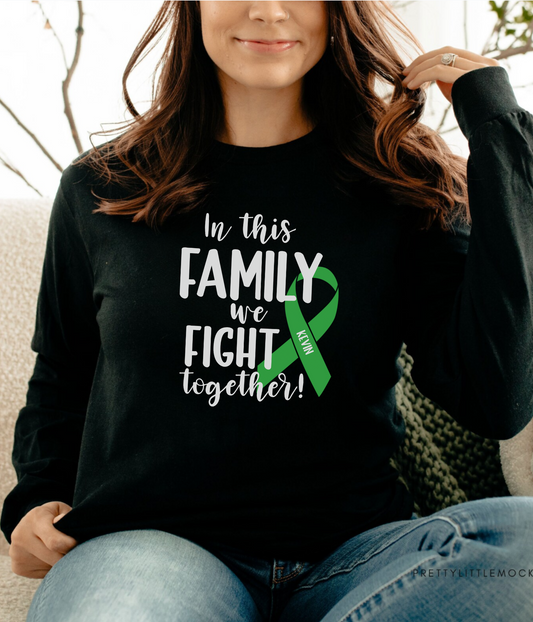 a woman sitting on a couch wearing a black shirt with a green ribbon