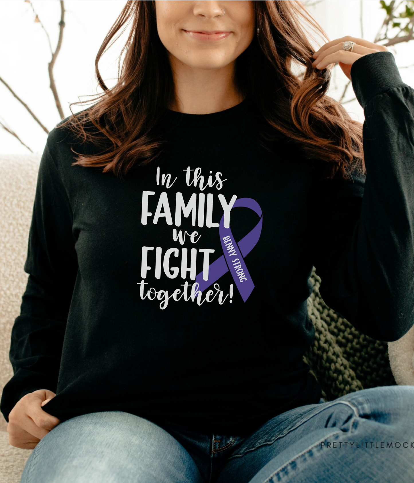 a woman sitting on a couch wearing a black shirt with a purple ribbon