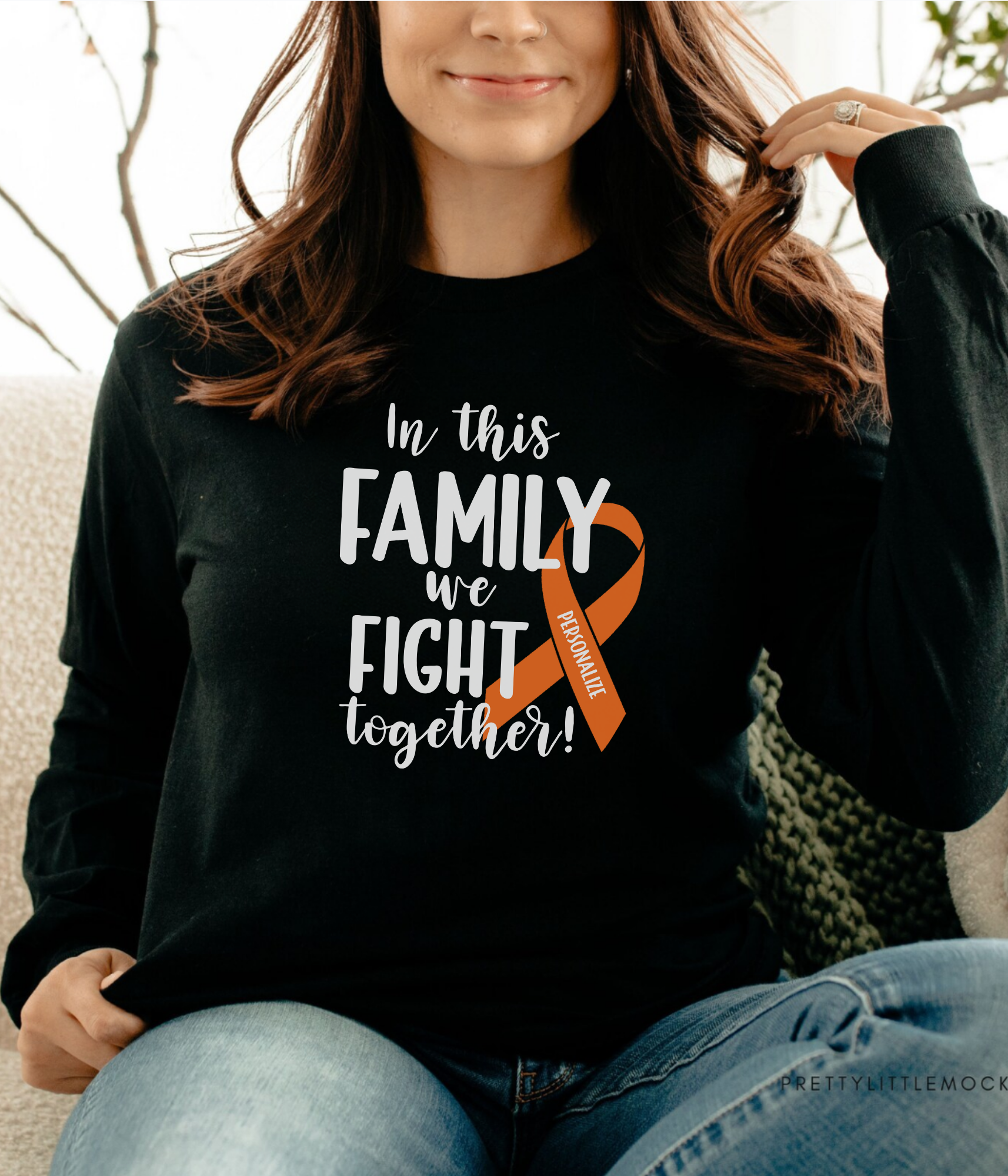 a woman sitting on a couch wearing a black shirt with an orange ribbon