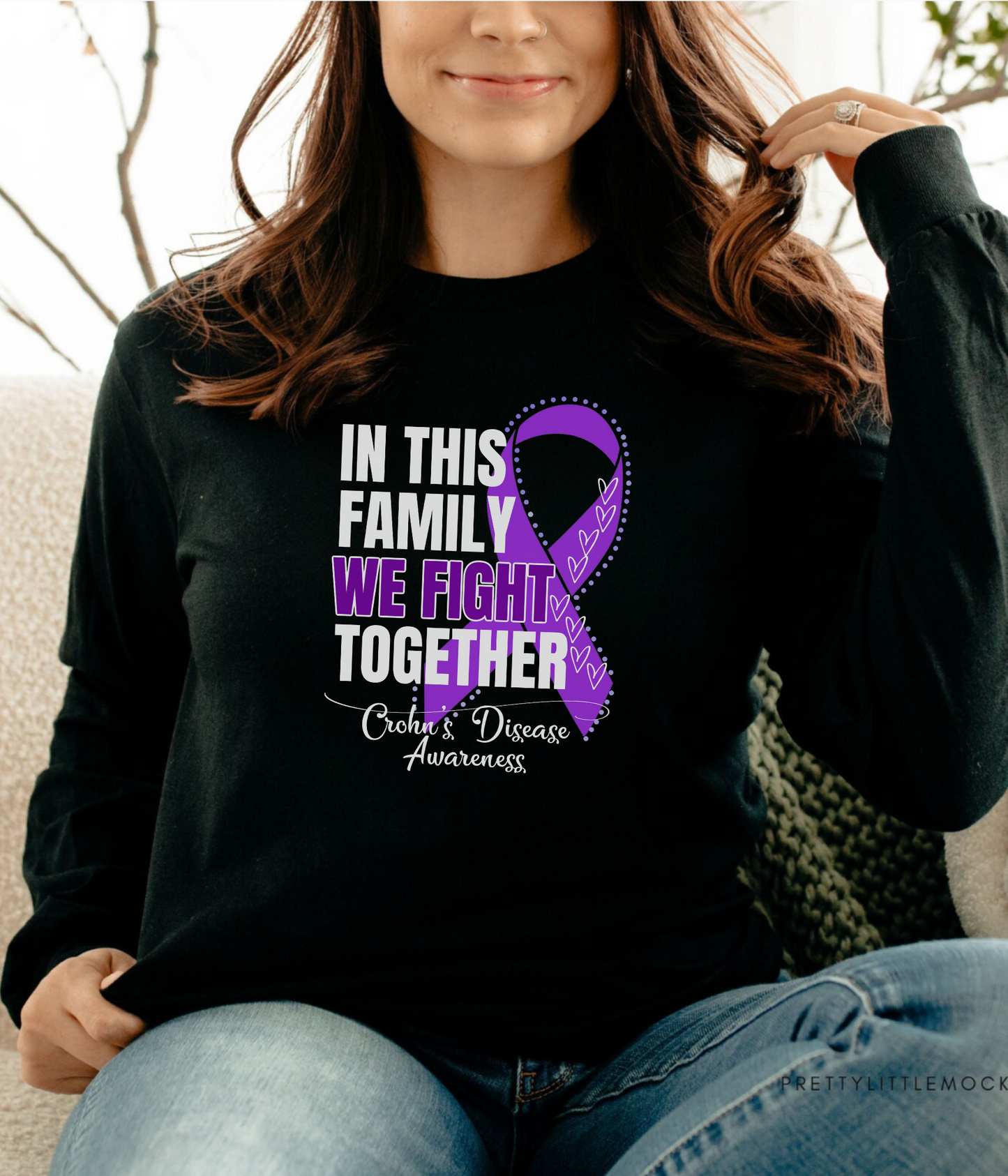 a woman sitting on a couch wearing a black shirt with a purple ribbon