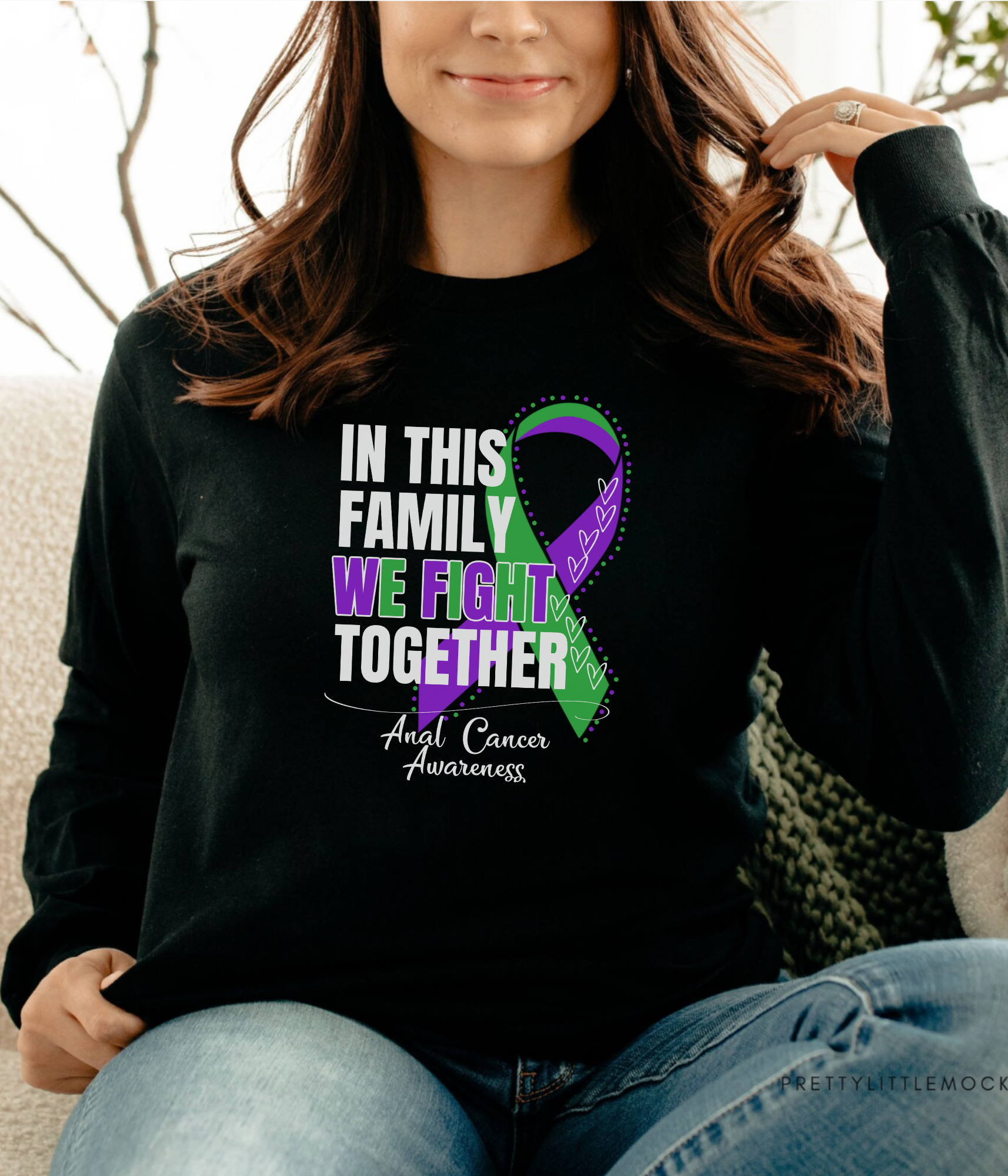 a woman sitting on a couch wearing a black shirt with a purple and green ribbon