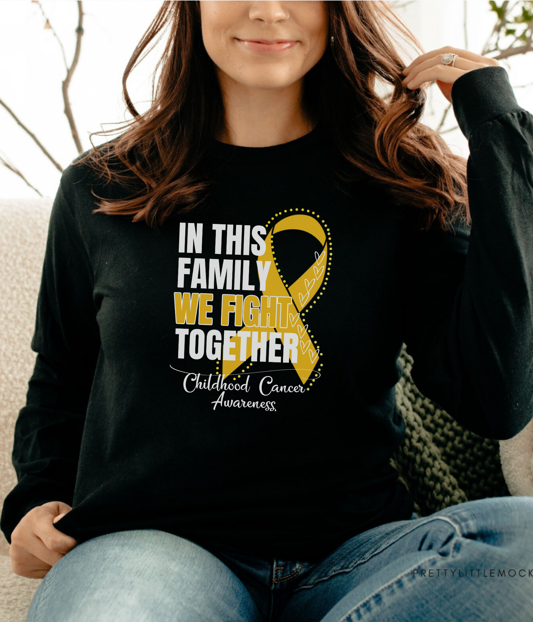 a woman sitting on a couch wearing a black shirt with a yellow ribbon